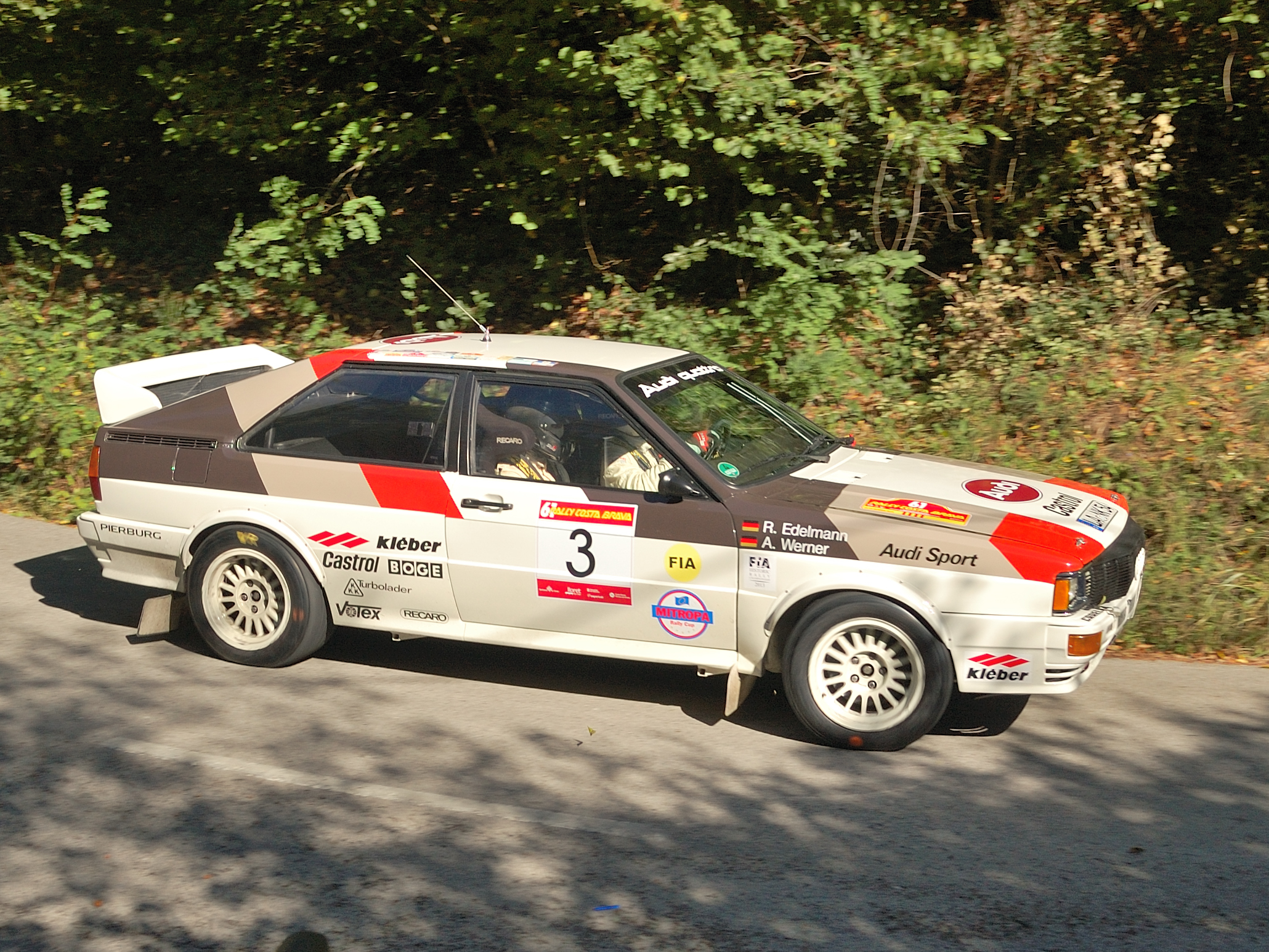 Weißer Audi quattro Rallyewagen in Fahrt auf einer Bergstraße